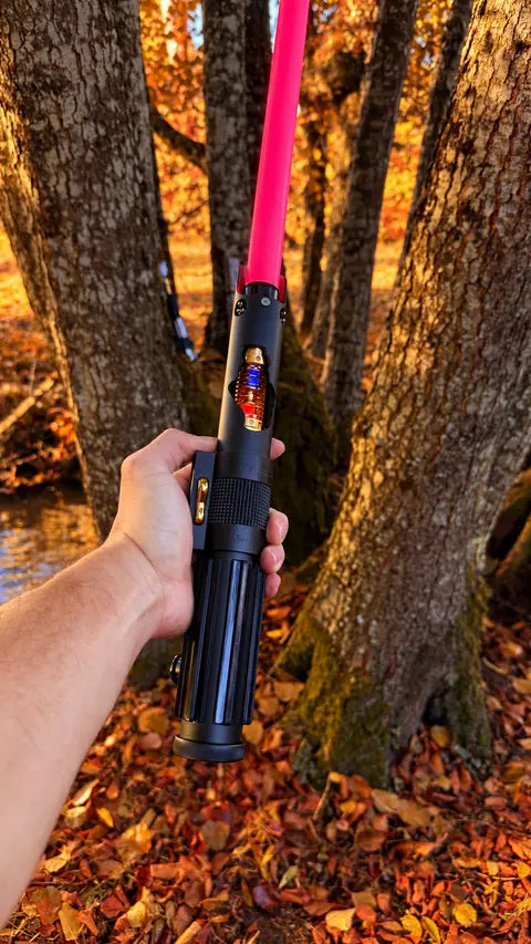 Sabre laser à lame rouge tenu en main dans la forêt