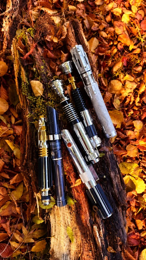 Plusieurs poignées de sabres laser disposées sur un tronc en automne