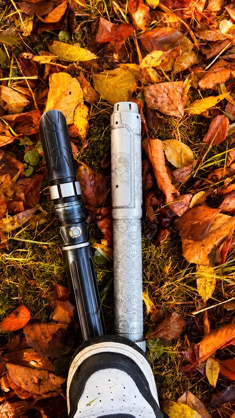 Deux poignées de sabres laser noire et argentée gravée sur les feuilles